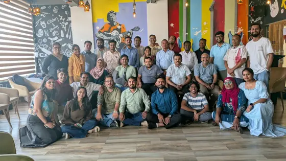 Group photo of about thirty people in a brightly painted room.