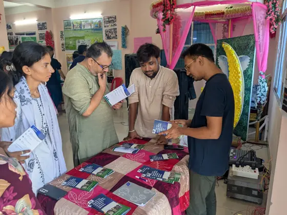 People looking at printed material on a table at the Act Now stall.