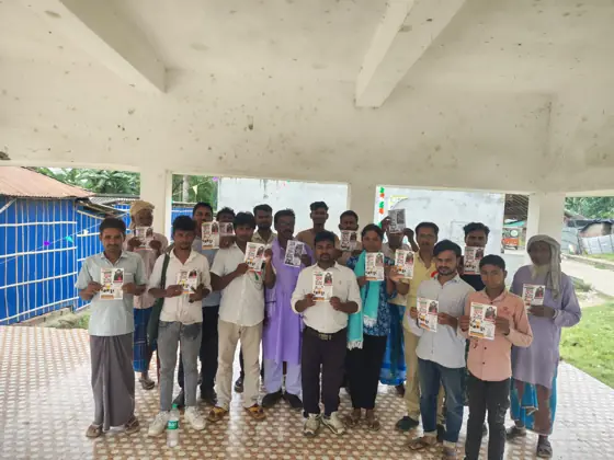 Workers standing in a row in an open hall, holding leaflets.