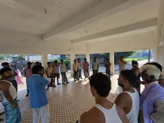 Men gathered in a circle in an open hall.