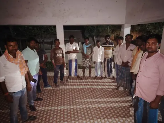 Workers standing in a circle in a hall with a patterned floor.