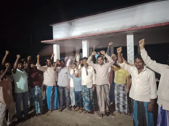 Workers raising their fists in front of a building at night.