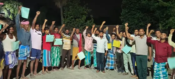 Workers raising their fists and holding papers at night.
