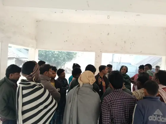 Men standing close together in a hall, listening.